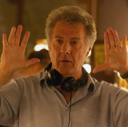 Man holding his hands up with headphones around his neck.