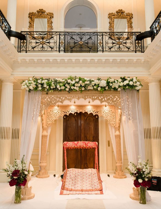 Red bench decorated with white roses at a South Asian wedding venue Hedsor House London