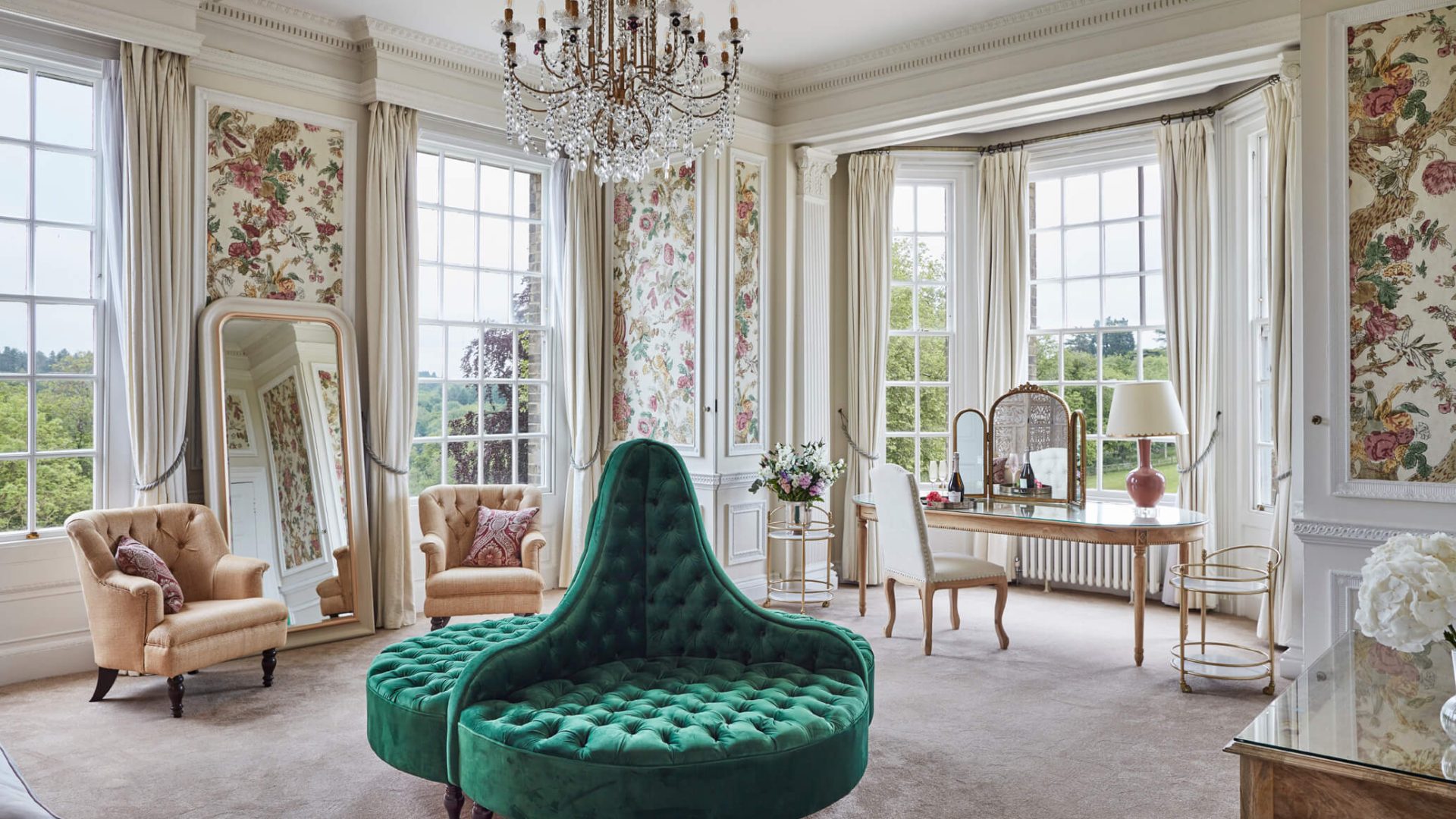 The spacious Lavina Suite with a large green sofa mirror and dressing table